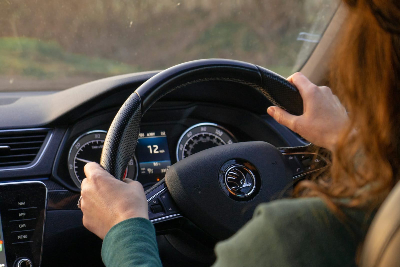 Jove conductora amb les mans al volant, llum natural de tarda — primera lliçó de conducció
